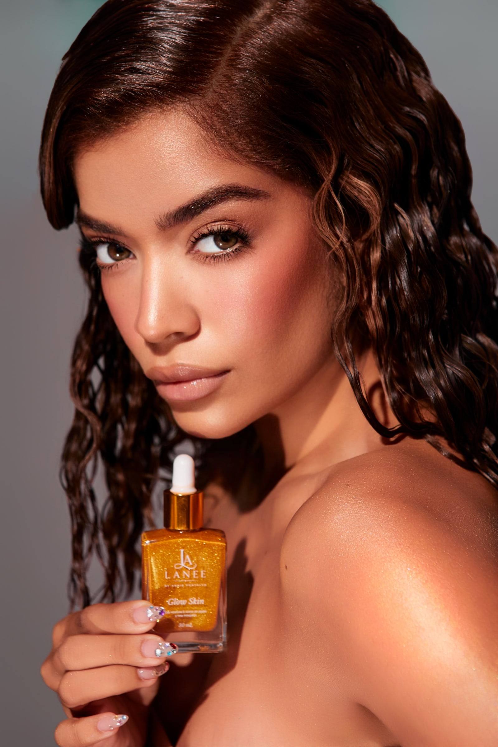 Modelo de cabello rizado con Glow Skin Gold junto al hombro